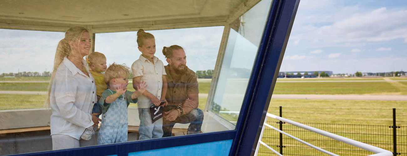 Een gezin kijkt vanuit de verkeerstoren naar buiten bij Aviodrome